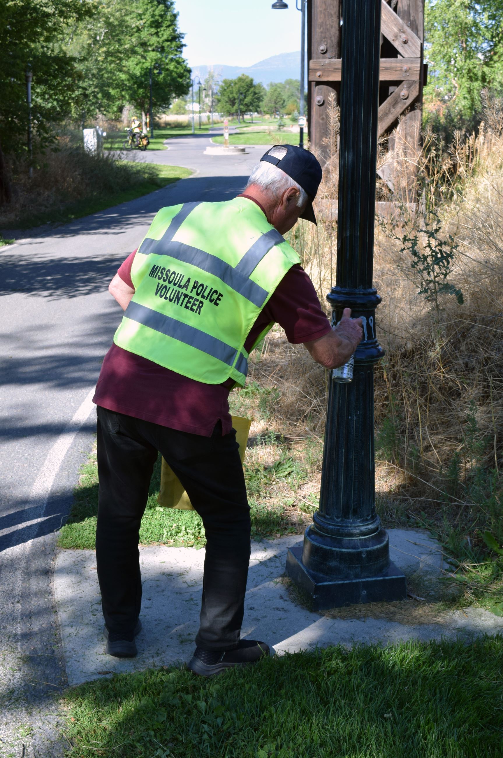 Volunteer covering graffiti on light pole