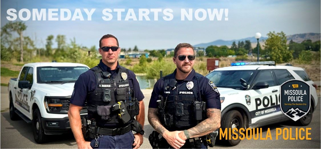 Two police officers with vehicles in background